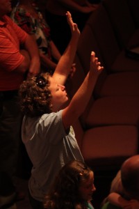 An individual worshiper praising Christ and lifting her hands to the heavens