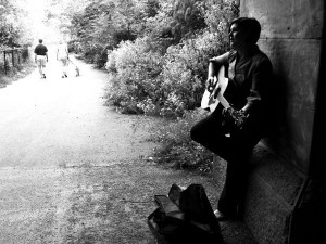 Indie singer-songwriter Kristen Gilles playing guitar outdoors on street