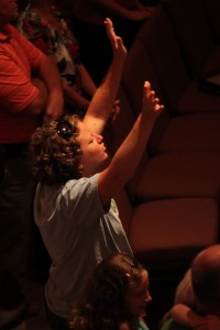 Woman raising hands in praise during Christian worship service at Sojourn Community Church